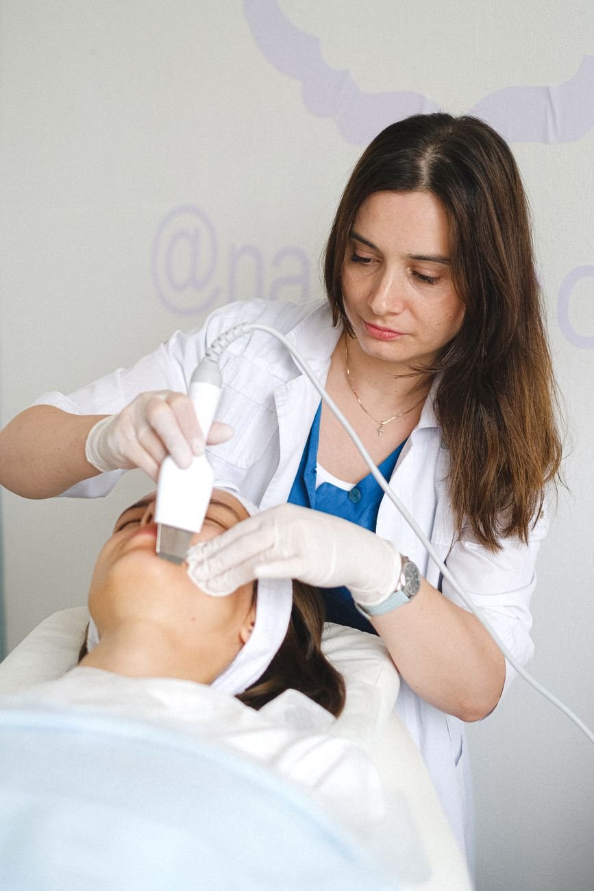 Especialista en estética avanzada en uniforme blanco trabajando con concentración en su cabina